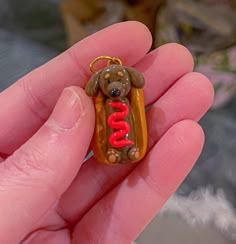 a hand holding a tiny toy dog with the word hotdog in it's mouth