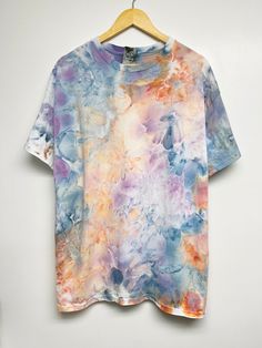 a colorful t - shirt hanging on a wooden hanger