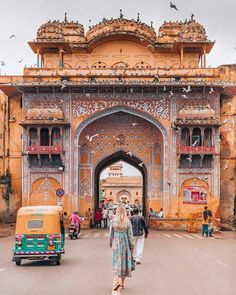 a woman walking in front of an ornate archway