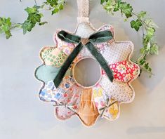 an ornament made out of fabric and ribbon hanging on a wall with ivy