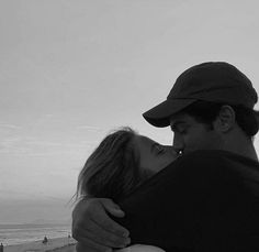 a man and woman embracing each other on the beach