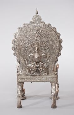 an ornate silver chair with carvings on it's back and foot rests against a white background