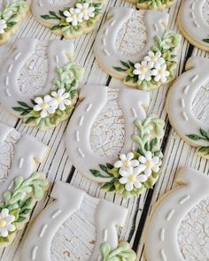 decorated cookies with white frosting and green leaves on wooden table next to each other