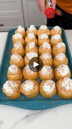 a tray filled with cupcakes on top of a counter next to a person