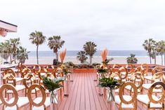 rows of chairs set up for an outdoor ceremony on the deck overlooking the ocean and palm trees