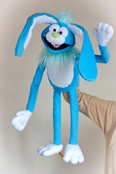 a person holding up a blue stuffed animal that looks like a bunny with long legs