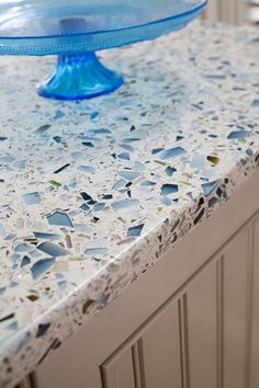 a blue cake plate sitting on top of a white countertop covered in glass shards