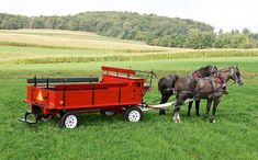 two horses pulling a red wagon in a field