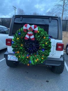 a christmas wreath is placed on the back of a jeep parked in a parking lot