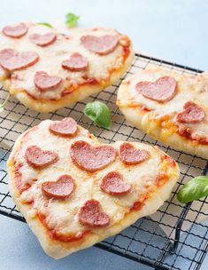 three heart shaped pizzas sitting on top of a cooling rack next to each other