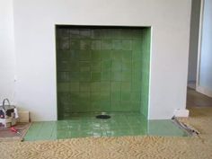 a green tile fireplace in a room with no one around it or the fire place