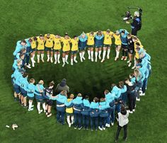 a group of people standing in the shape of a circle on top of a field