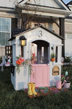 a doll house with flowers and rain boots on the lawn