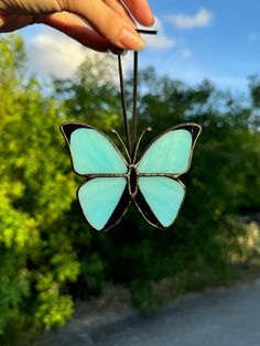 a hand holding a small blue butterfly ornament