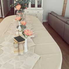 a table with flowers and books on it in front of a white china hutch