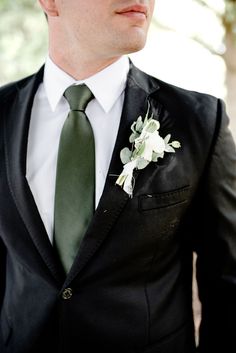 a man wearing a suit and tie with a boutonniere on his lapel