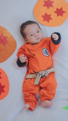 a baby laying on top of a bed wearing an orange outfit