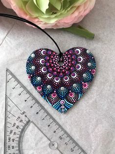 a heart shaped ornament sitting next to a ruler