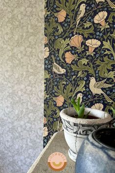 a potted plant sitting on top of a table next to a wallpapered wall