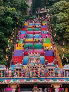 colorful steps leading up to the top of a hill with statues on each one side