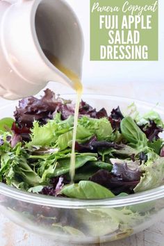 a salad in a bowl with dressing being poured into it and on top of the salad