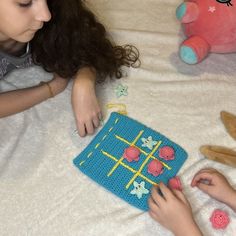 two children playing with crochet toys on a bed in front of a stuffed animal