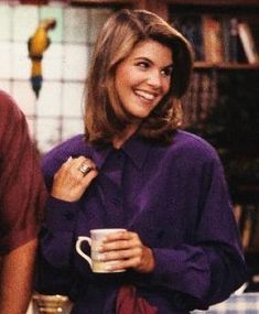 a smiling woman holding a coffee cup in her right hand