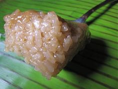 a piece of food that is on top of a banana leaf with chopsticks