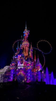 the disneyland castle is lit up at night with lights and decorations on it's side