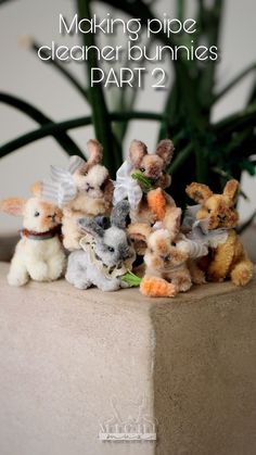 a group of stuffed animals sitting on top of a cement block next to a plant