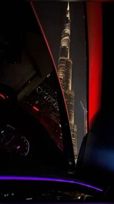 the burj tower is lit up at night from inside a car window with its lights on