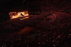 an aerial view of a concert venue at night, with the stage lit up in red and yellow