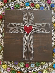 a wooden cross with a red heart in the center on a doily covered table