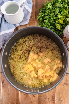 a pot filled with food sitting on top of a wooden table next to garlic and parsley