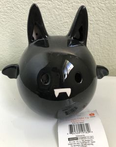 a black cat shaped object sitting on top of a white table next to a barcode