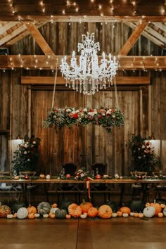 a table with chandelier and pumpkins on it in front of a wooden wall