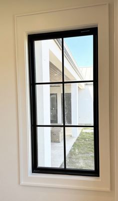 an open window on the side of a white building with grass in front of it