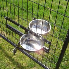 two stainless steel bowls sitting on top of each other in a fenced off area