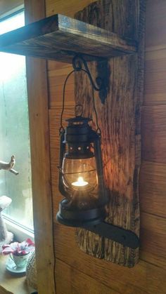 an old fashioned lantern hanging on the side of a wooden wall next to a window