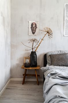 a bed sitting next to a wooden table with a vase filled with flowers on top of it