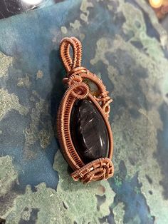 "Hypersthene is a very beautiful stone. It shines like labradorite when you move it around at different angles. Has black and silver, gray shine. This piece is wire wrapped in copper wire, with a unique intricate frame. I added a stunning tibetan agate stone to add character to the whole piece. This pendant would be an amazing and unique gift for friends and loved ones. Many individuals use stone as healing crystals. It is up to you to decide what your intentions are. Dimensions:  1\" Tall 1\" Wide .25\" Thick All of my wire wraps are hand weaved by me. Shipping is free with insurance. I price my wire weaved pendants based on the weight of the stone, by price per gram, and how long it took me to wire wrap each stone, as well as the price on the potency and quality of my minerals, and the a Wire Wrap Tumbled Stone, Bohemian Black Wire Wrapped Necklace, Bronze Wire Wrapped Spiritual Necklace, Masculine Wire Wrap Pendant, Spiritual Wire-wrapped Metal Crystal Necklace, Handmade Wire Jewelry, Wrapped Pendant, Copper Pendants, Agate Stone