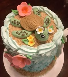 there is a cake that looks like a turtle on top of the sand and flowers