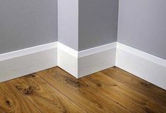 the corner of a room with wood flooring and white trim on it's walls