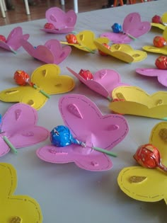 paper plates with hearts and candies on them sitting on a white tablecloth covered table