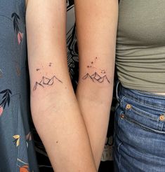 two people with matching tattoos on their arms, one is holding the other's arm