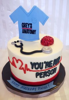 a birthday cake with a stethoscope and nurse's t - shirt on top