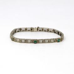 Phenomenal antique Art Deco Era 14k white gold filigree simulated emerald bracelet! This piece features three square cut bezel set simulated emerald stones (garnet glass doublets - very common of this time period). The dainty bracelet's panels are detailed with intricate pierced filigree with sweet flower motifs. There is a filigree clad box clasp closure. A gorgeous piece of fine jewelry, circa 1920s! Such a detailed and stunning bracelet from the roaring '20s, which would make a lovely bridal piece!  ERA - Circa 1920, Art Deco Era METAL / MATERIAL - 14k white gold, three simulated emeralds (garnet glass doublets) MARKINGS / HISTORY - Clasp is stamped 14k CONDITION - Good vintage condition. Designs are beautifully preserved. Piece has been professionally cleaned and lightly polished. Ston Filigree Bracelet, Flower Motifs, Emerald Bracelet, Logo Gifts, 1920s Art, Roaring 20s, 1920s Art Deco, Box Clasp, Dainty Bracelets