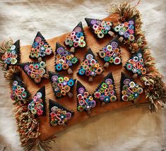 a bunch of colorful buttons sitting on top of a wooden board with fringes around them