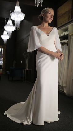 a woman in a white dress standing next to a chandelier