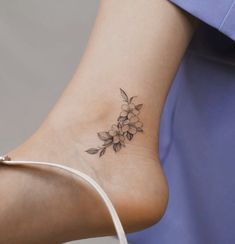 a woman's foot with a flower tattoo on the side of her ankle,